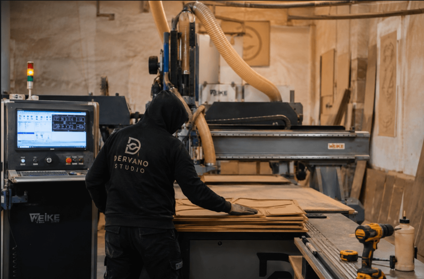 Master craftsman inspecting CNC-cut wood panels at the workbench — quality control and hand-finishing process at Dervano Studio.